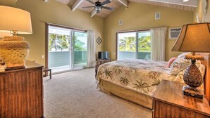 A bedroom with a bed, two nightstands, a ceiling fan, and large sliding glass doors leading to a balcony.