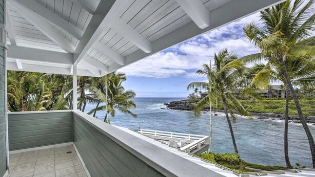 A balcony with a view of the ocean and palm trees.