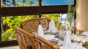 A dining table set for two with a view of the ocean through large windows. - Best of Kaanapali Ali'i Suite 382 - Walk Whalers Village - Ocean Views (Lahaina)