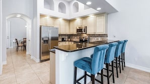 Cocina moderna con una isla central, electrodomésticos de acero inoxidable y un comedor con mesa y sillas.