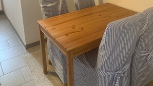 Een eetruimte met een houten tafel en gestreepte stoelen. Twee plaquettes aan de muur met tekst.