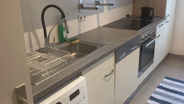 Een moderne keuken met een inbouw wasmachine, een koffiezetapparaat en een vaatwasser.