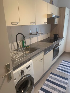 A modern kitchen with a built-in washing machine, a coffee maker, and a dishwasher. - Apartment at Griesplatz (Graz)
