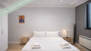 Un dormitorio moderno con una cama grande, dos mesitas de noche, una lámpara de pie y un radiador.