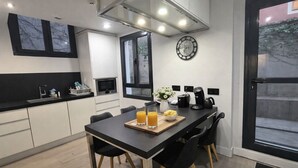 Una cocina moderna con una mesa de comedor, sillas, un reloj y una cafetera.