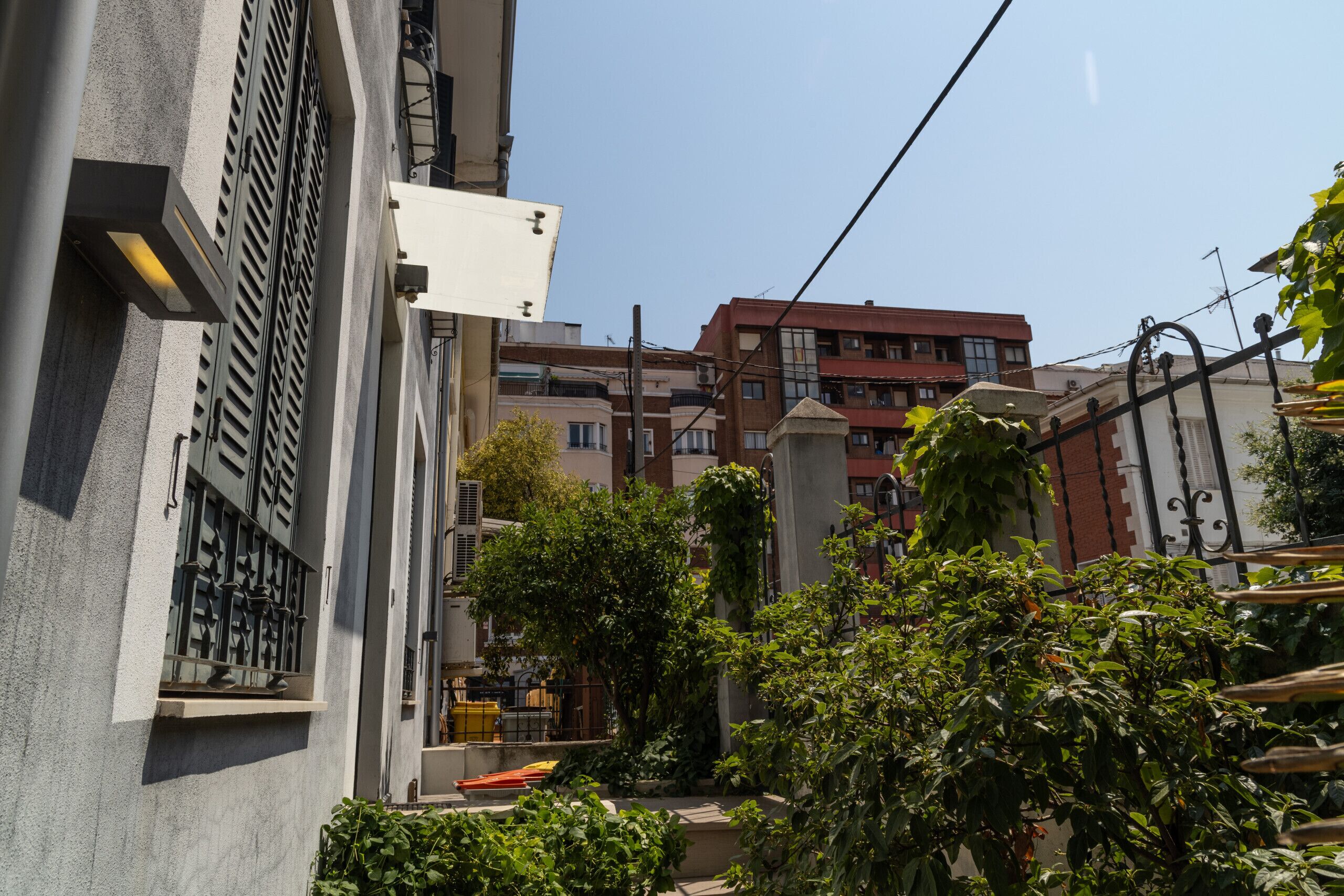 A residential building with balconies, a garden area, and a clear sky.
