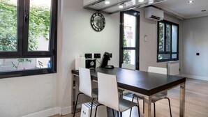 Une cuisine moderne avec un plan de travail foncé, des chaises blanches et une horloge au mur.
