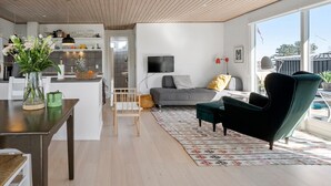A modern living space with a kitchen, dining area, and a seating area with a sofa and armchair. - 2 bedroom cozy home in Kerteminde (Kerteminde)
