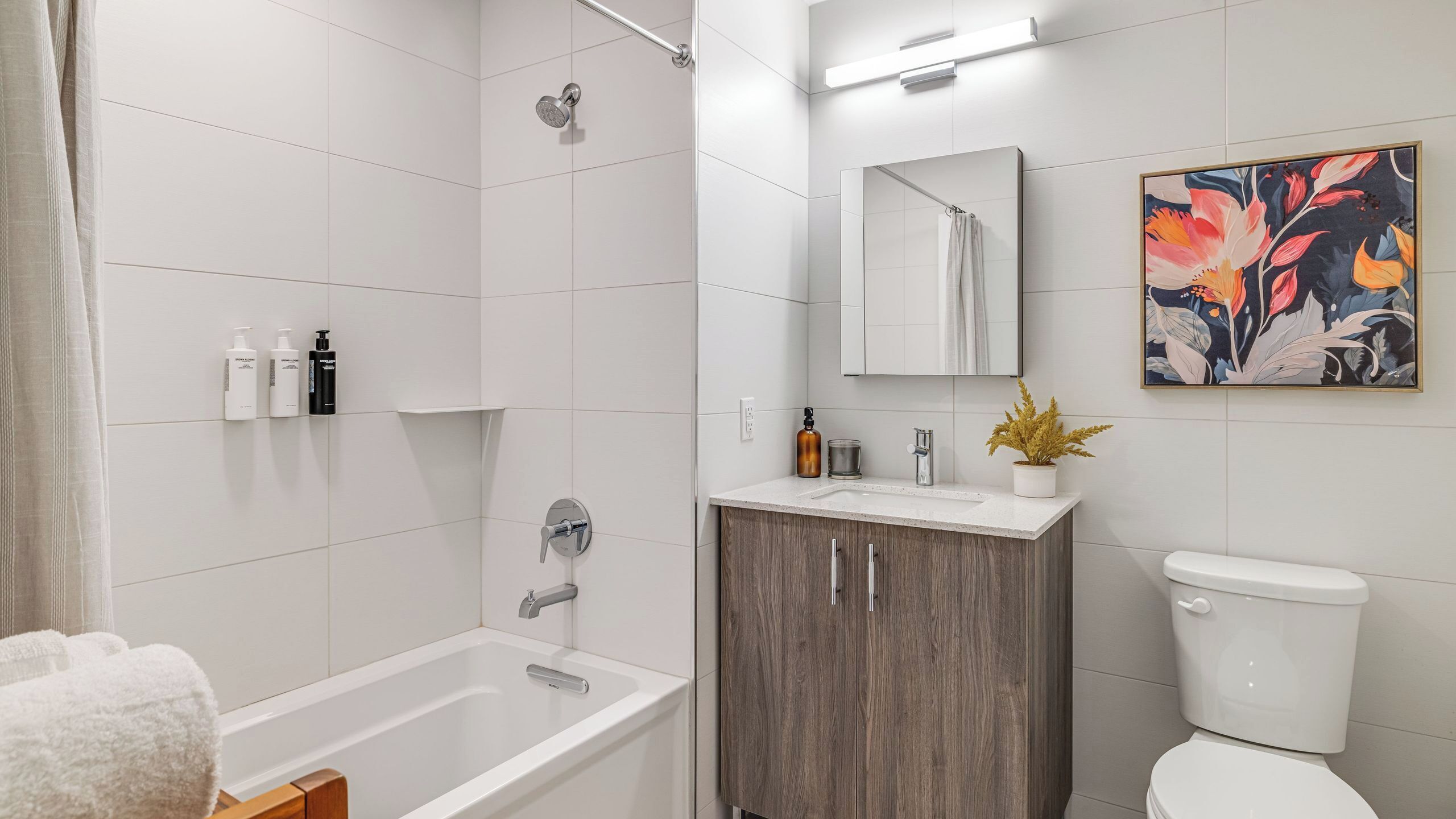 A modern bathroom with a bathtub, toilet, vanity, and a shower.