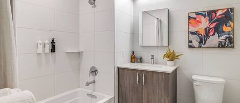A modern bathroom with a bathtub, toilet, vanity, and a shower.