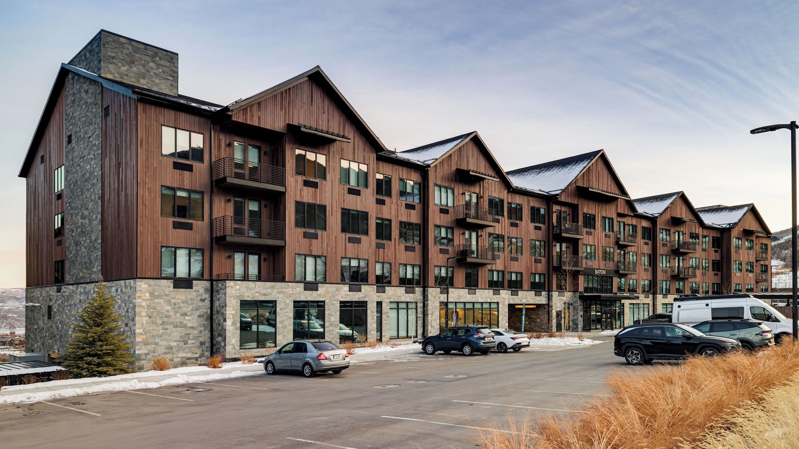 A multi-story hotel with a stone facade, balconies, and a parking lot.