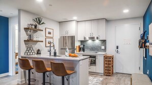 A modern kitchen with a central island, bar stools, and stainless steel appliances.