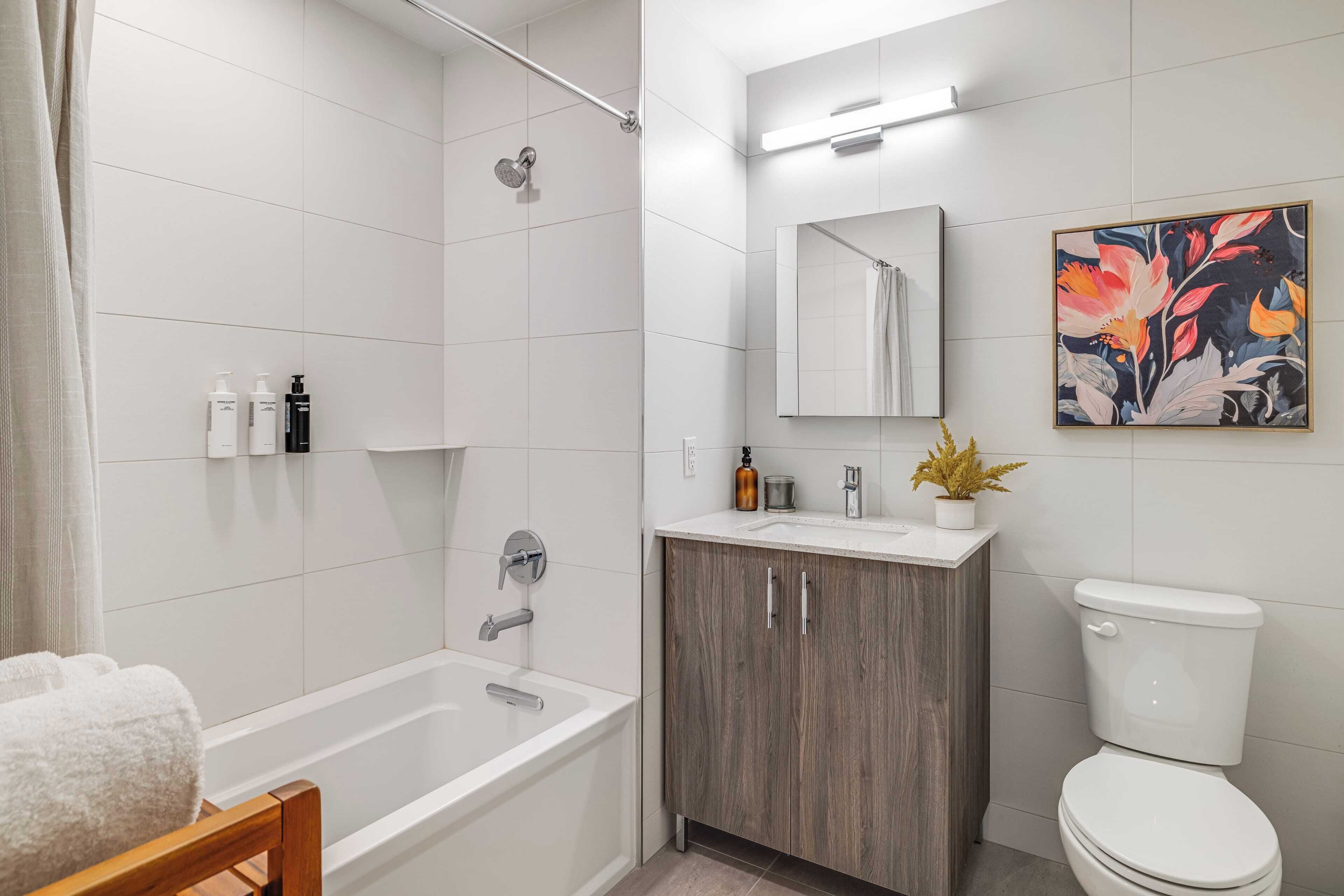 Une salle de bain moderne équipée d’une baignoire, de toilettes et d’un meuble-lavabo avec un miroir.