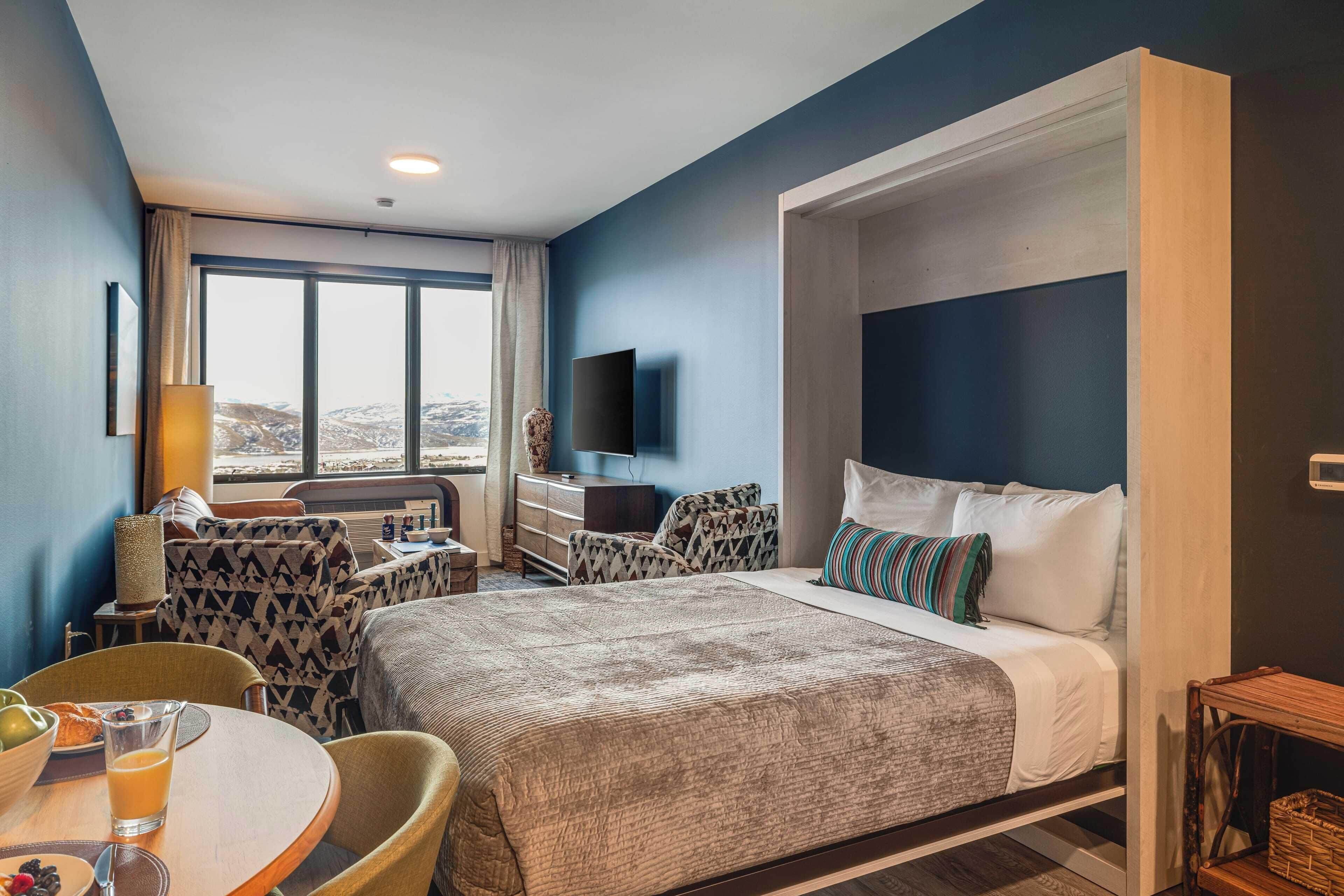 A hotel room with a large bed, a desk, a chair, and a TV.