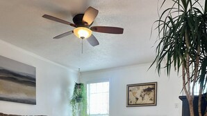 Un salon spacieux doté d’un plancher en bois franc, de deux canapés, d’un ventilateur de plafond et d’une grande fenêtre.