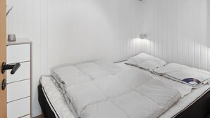 A bedroom with a bed, a bedside table, and a wardrobe. - Cozy summer house close to beach and nature (Rønde)