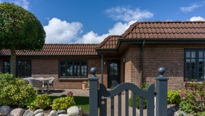 A brick house with a tiled roof, a stone wall, and a metal gate. - Beach Bungalow Sylt 1 - Welcome to your private paradise in the middle of the (Sylt OT Rantum)