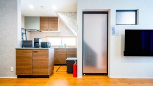 A modern kitchen with wooden cabinets, a coffee machine, and a fire extinguisher. - SHIRAKABA (Otaru)