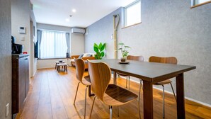 A modern dining area with a wooden table and chairs, a small round table, and a potted plant. - SHIRAKABA (Otaru)