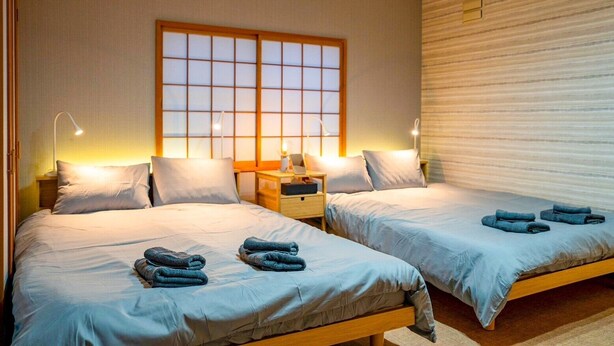 A hotel room with two beds, a large window, and a wooden headboard. - SHIRAKABA (Otaru)