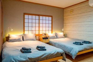 A hotel room with two beds, a large window, and a wooden headboard. - SHIRAKABA (Otaru)