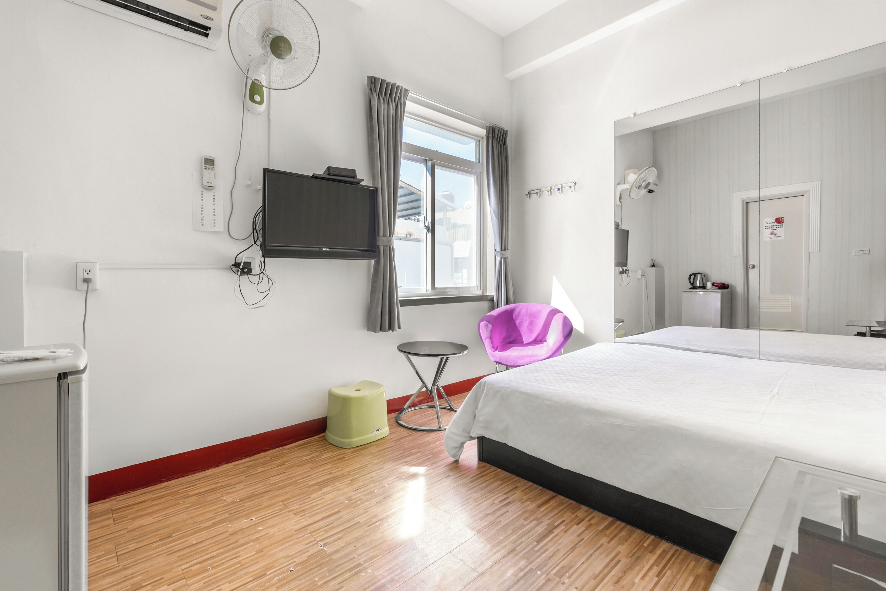 Habitación de hotel con cama, televisión, ventana con cortinas, una silla y una mesita.