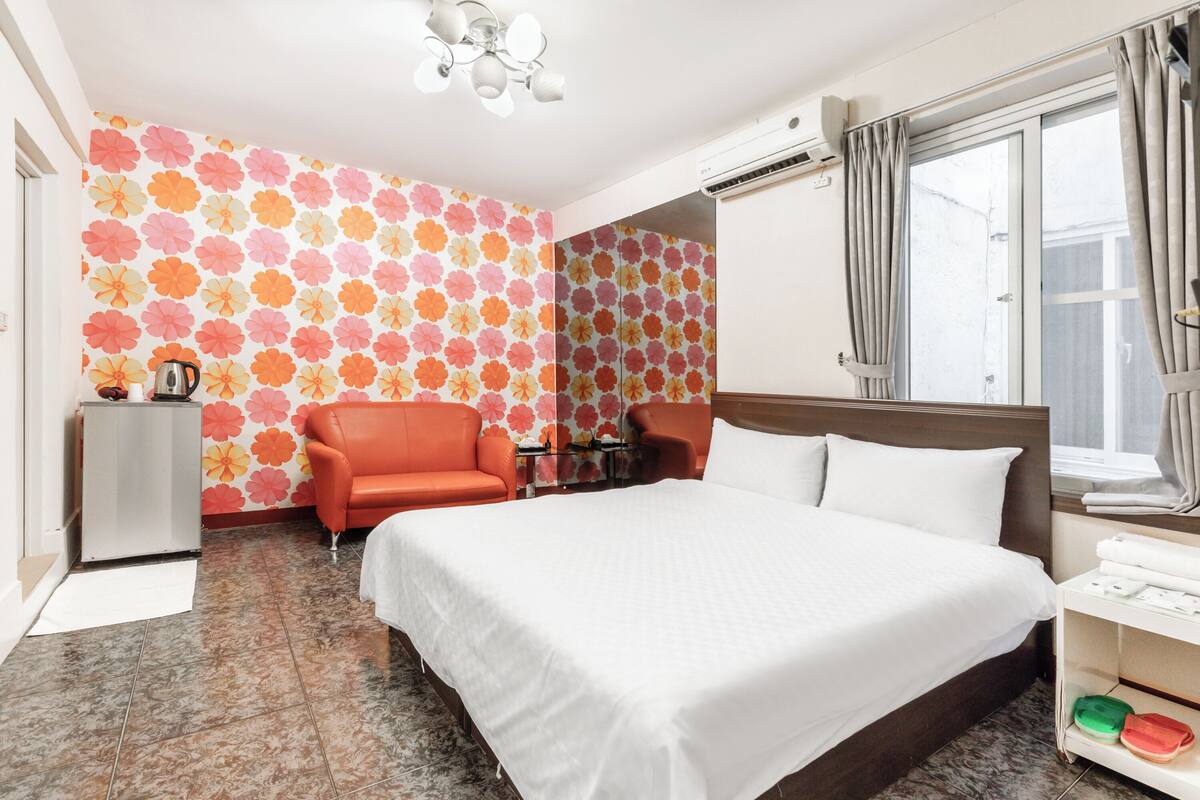 Ein Hotelzimmer mit einem großen Bett, zwei Sesseln, einem kleinen Tisch und einer Minibar.