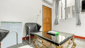 A room with a glass-top table, a black leather chair, a wooden door, and a window with curtains. - Rich house (Hengchun)