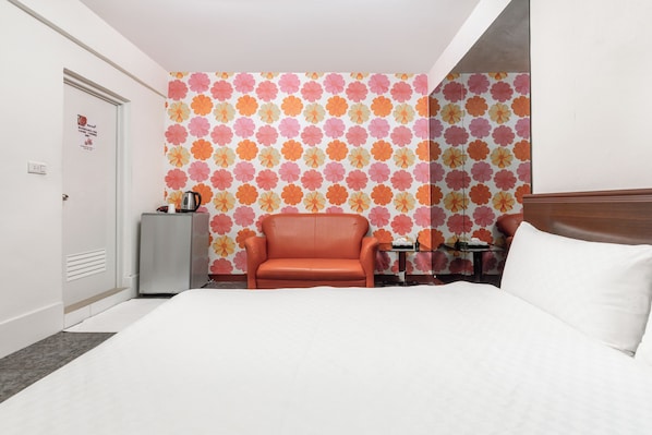 Une chambre d’hôtel avec un lit, un fauteuil en cuir, une petite table avec une lampe et un mur décoratif.