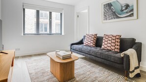 A modern living room with a grey sofa, patterned cushions, a wooden coffee table, and a framed artwork on the wall. - Blueground | Fitzrovia, nr museum & park, w/d (London)