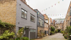 A narrow cobblestone street lined with traditional brick buildings, some with visible windows and doors. - Blueground | Fitzrovia, nr museum & park, w/d (London)