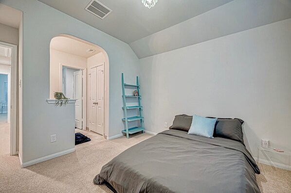 A bedroom with a bed, a blue shelving unit, and a door leading to another room. - Katy Lake home retreat! (Katy)
