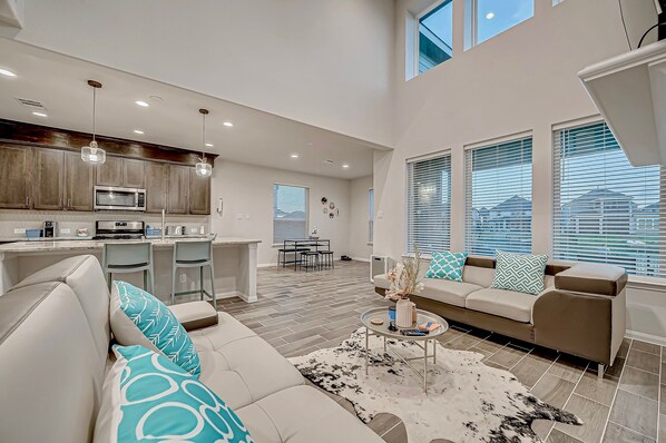 A spacious living area with a sofa, coffee table, and a dining area with chairs and a table. - Katy Lake home retreat! (Katy)