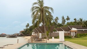 A swimming pool with clear water, surrounded by palm trees and a beach in the background. - Sadi Beach House (Bintan)
