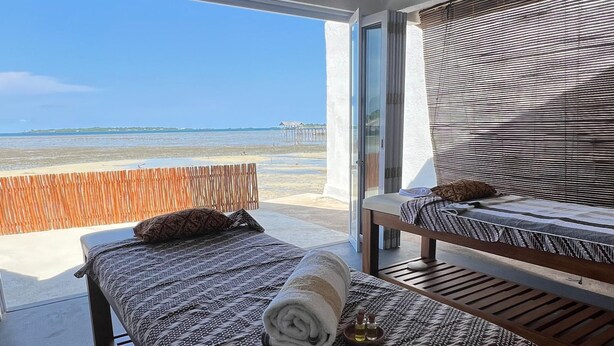 A room with a bed, a table, and a view of the beach. - Sadi Beach House (Bintan)