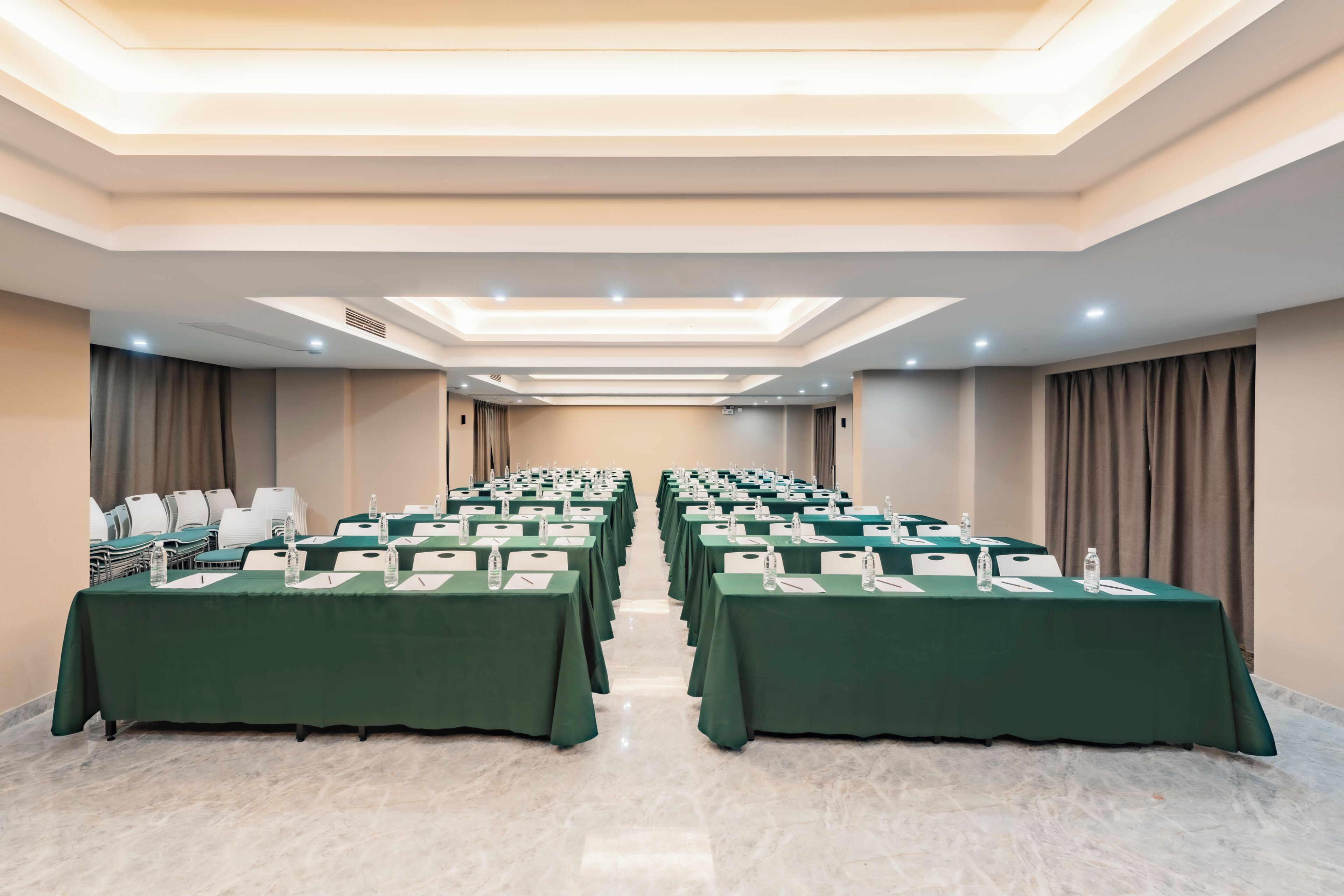 A conference room with rows of tables, chairs, and a ceiling with recessed lighting.