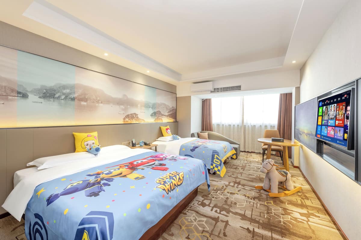 Una habitación de hotel con dos camas, televisión, escritorio y sofá.