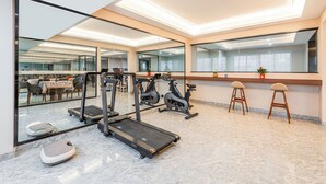 Ein Fitnessstudio mit Laufbändern, Crosstrainern und einer Spiegelwand.