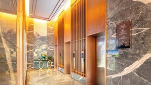 Eine Hotelhalle mit Marmorböden, Holzvertäfelung und einer Marmorwand mit einer Schrifttafel, die Zimmer und Annehmlichkeiten ausweist.