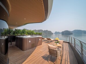 A modern deck with a hot tub, lounge chairs, and a view of the water and mountains. - Calista Cruise - A Ha Long Bay Spectacle (Tuan Chau)
