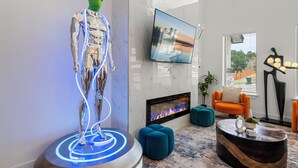 A modern living room with a fireplace, a television, and a unique sculpture. - Space-themed retreat w/pickleball, hot tube,games. Aliens and astronauts, await! (Marble Falls)
