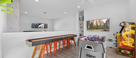 Een moderne keuken met een bar, een tafelvoetbaltafel en een groot raam met uitzicht op de bergen.
