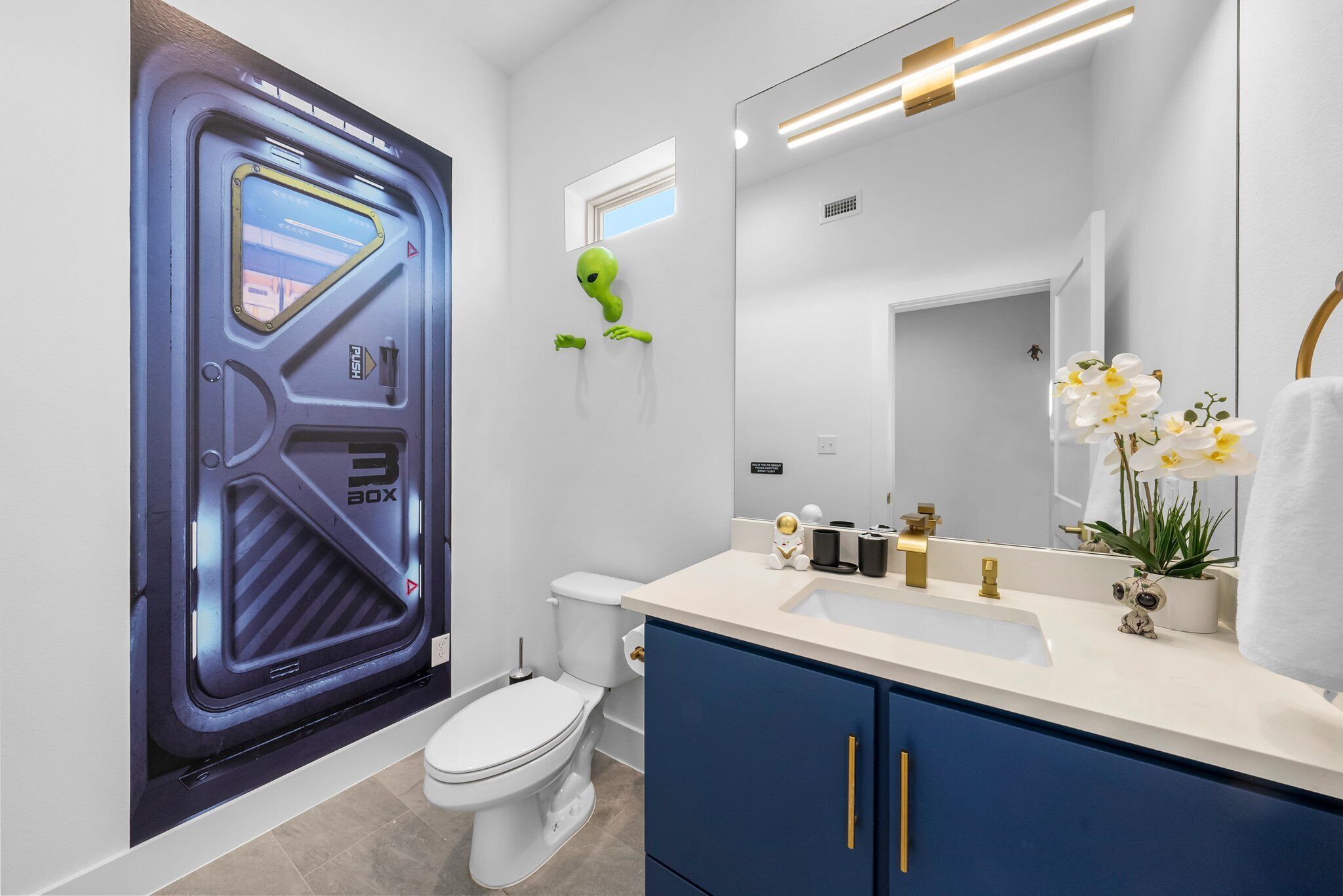 A modern bathroom with a large mirror, a toilet, and a sink.