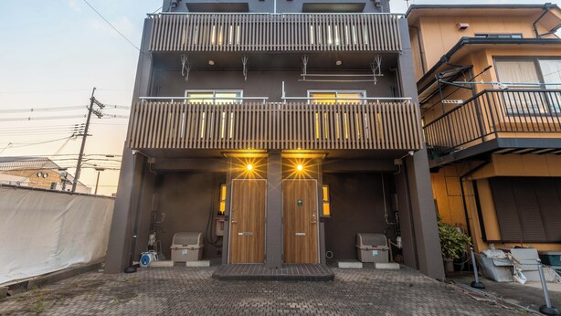 Un bâtiment moderne doté d’une entrée à deux niveaux, de portes en bois et d’un balcon agrémenté de balustrades.