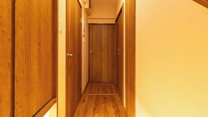 Un couloir étroit, avec des portes en bois de chaque côté, qui mène à une porte fermée au bout.
