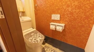 A bathroom with a toilet, sink, and towel dispenser.
