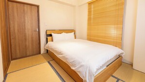 Une chambre avec un lit en bois, une porte en bois et une fenêtre avec des stores.