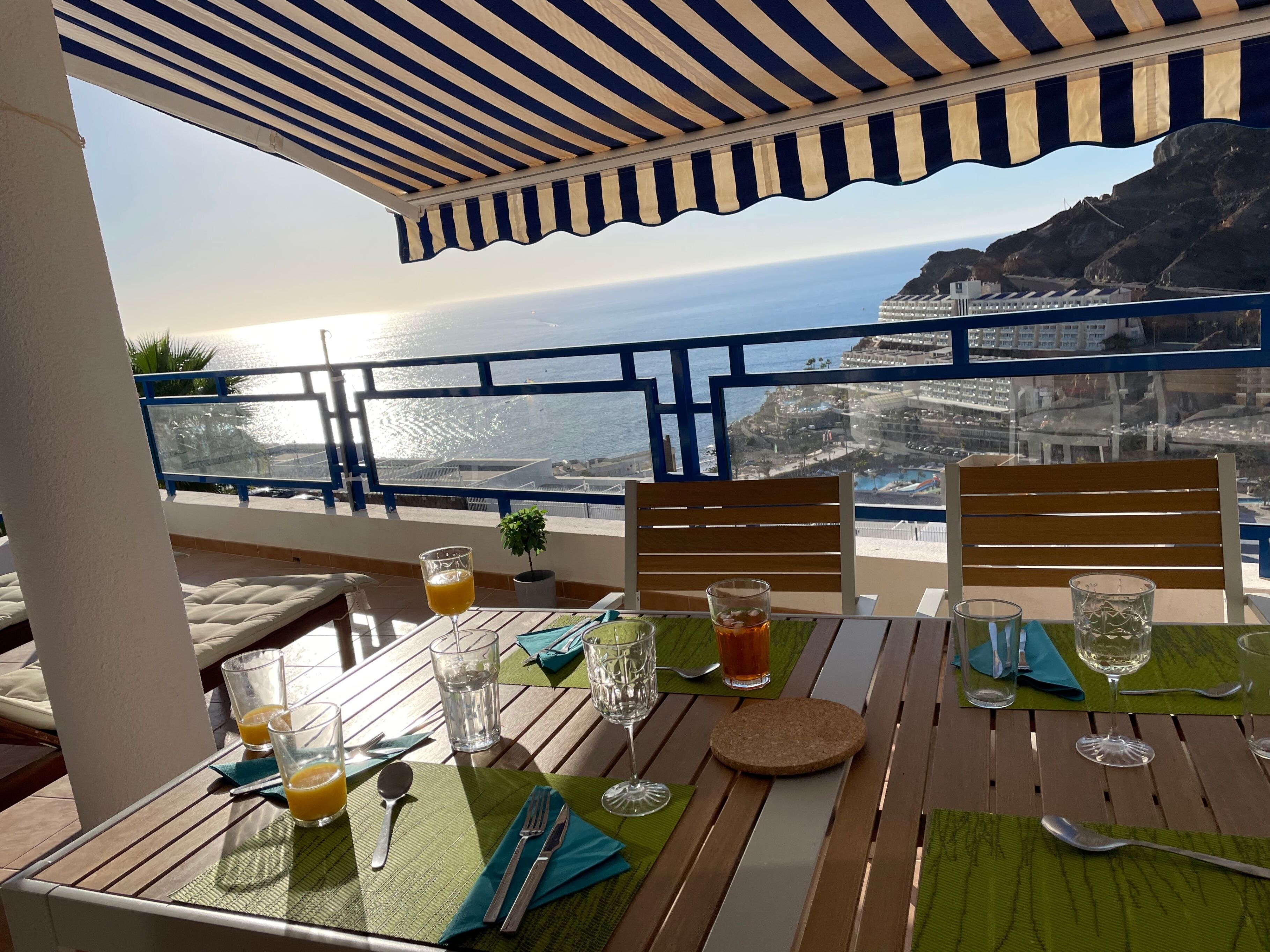 A table set for two with a view of the ocean and a cityscape.