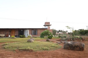 A brick house with a small tower, surrounded by a landscaped garden with rocks and plants.