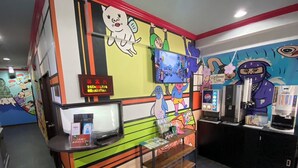 A brightly colored counter with a television, vending machines, and a sign indicating a restroom. - Sakura Osaka Castle North Hotel (Osaka)
